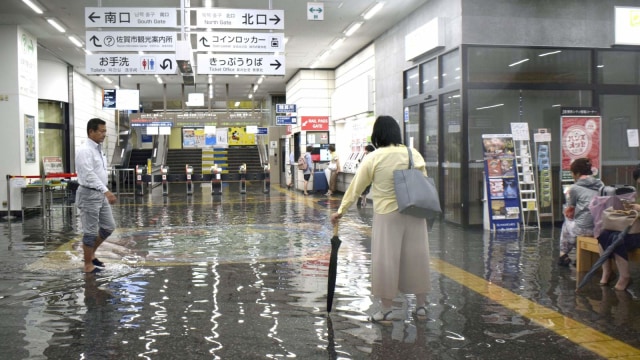 Warga berjalan di Stasiun Saga yang tergenang Banjir. Foto: Kyodo / via REUTERS