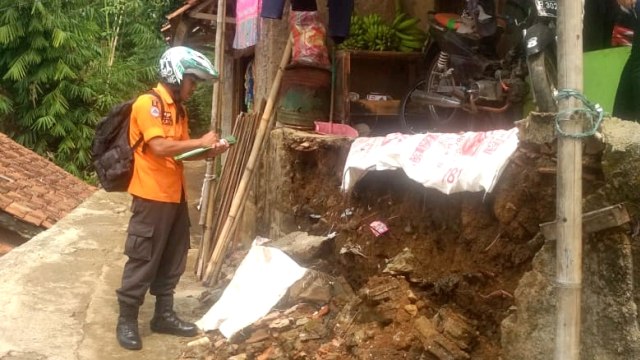 Petugas BNPB mengecek kondisi rumah rusak akibat tanah longsor di Bogor. Foto: Dok. BNPB