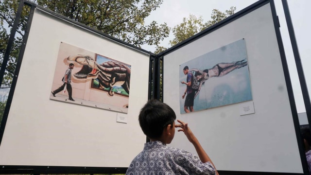Seorang siswa mengamati pameran foto 'Rekam Jakarta 2018' yang diselenggarakan Pewarta Foto Indonesia Jakarta di Taman Menteng, Jakarta, Kamis (29/8). Foto: Irfan Adi Saputra/kumparan