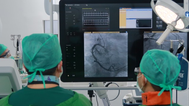 Tim dokter saat melakukan tindakan operasi kateterisasi jantung dengan mesin azurion. Foto: Aditia Noviansyah/kumparan
