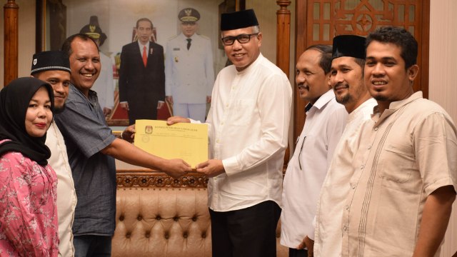 Wakil Ketua KIP Aceh, Tharmizi menyerahkan berkas calon anggota DPR Aceh terpilih kepada Plt Gubernur Aceh, Nova Iriansyah. Foto: Yudiansyah/acehkini