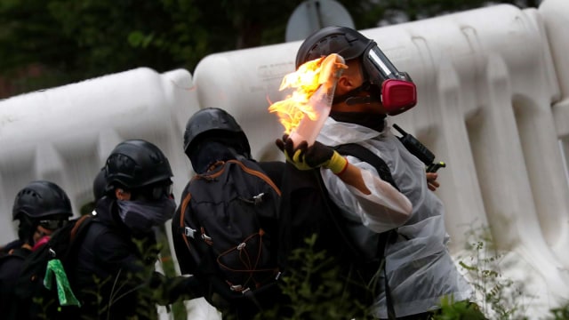 Seorang demonstran melemparkan bom molotov saat aksi protes di Hong Kong. Foto: REUTERS / Kai Pfaffenbach
