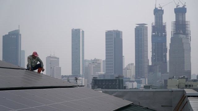 Petugas melakukan pemeriksaan instalasi panel surya di atap kantor PP Muhammadiyah, Jakarta. Foto: Jamal Ramadhan/kumparan