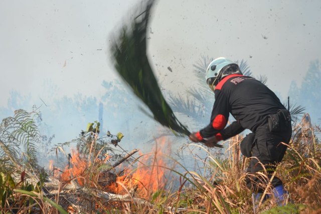 Petugas berupaya memadamkan api yang membakar lahan di Kabupaten Sintang. Foto: Agus Pujianto/Hi!Pontianak