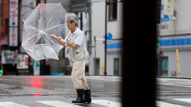 Seorang pria kesulitan menggunakan payung saat Topan Faxai di Tokyo, Jepang, Senin (9/9). Foto: REUTERS/Issei Kato
