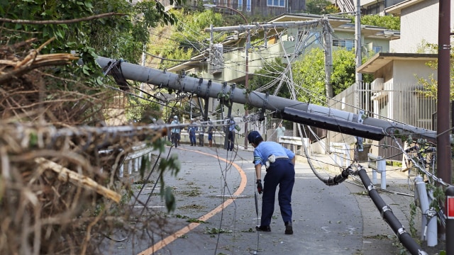 Seorang polisi mengecek tiang listrik yang rubuh akibat Topan Faxai di Kamakura, Prefektur Kanagawa, Senin (9/9). Foto: AFP/JIJI PRESS