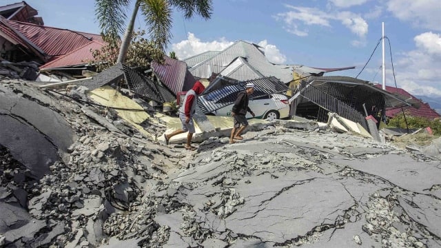 Warga melintasi jalanan yang rusak akibat gempa 7,4 pada skala richter (SR), di kawasan Kampung Petobo, Palu, Sulawesi Tengah. (Foto: ANTARA FOTO/Muhammad Adimaja)