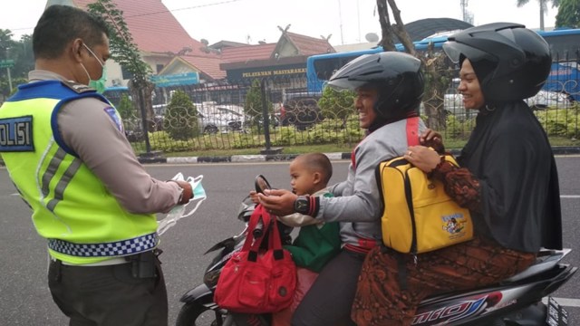 Polisi lalu lintas (Polantas) Polda Riau membagikan masker kepada pengendara sepeda motor. 