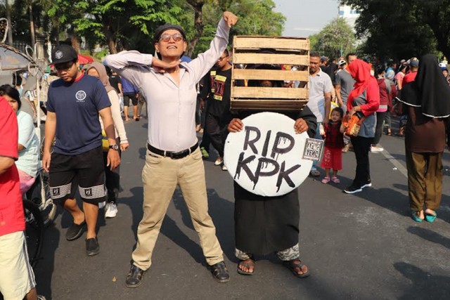 Seorang warga mengenakan keranjang kotak dikepalanya dan berkalungkan tulisan “RIP KPK”. (Fernando Fitusia)