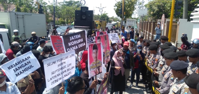 Massa berunjuk rasa di Kejari Sampang membawa poster Kades Sokobanah Daya Pak Jatem untuk segera ditangkap yang diduga korupsi dana desa tahun 2018, Senin (16/9/2019). (Zainal/MM). 