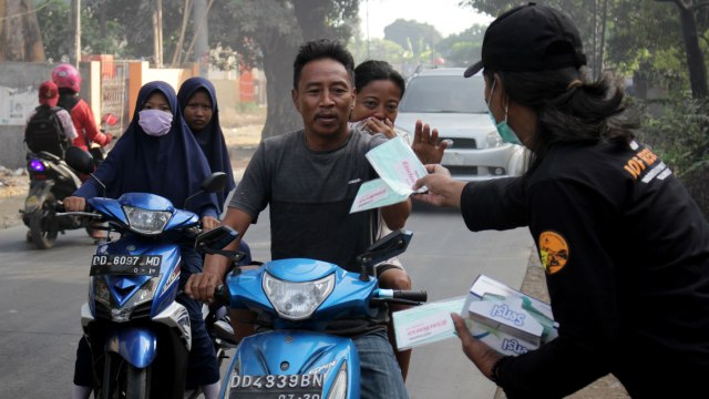 Warga menerima masker secara gratis dampak kebakaran TPA Antang di Kecamatan Manggala, Makassar, Sulawesi Selatan, Rabu (18/9/2019). Foto: ANTARA FOTO/Abriawan Abhe
