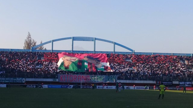 Bentangan koreo merah putih dengam 2 suporter salih berangkulan di lanjutan Shopee Liga 1 2019 di Stadion Maguwoharjo, Sleman, Kamis (19/9/19). Foto: atx.