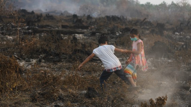 Anak-anak bermain di area kebakaran lahan gambut di kawasan Landasan Ulin, Banjarbaru, Kalimantan Selatan, Kamis (19/9/2019).  Foto: ANTARA FOTO/Bayu Pratama S