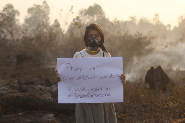 Galeri Foto Pilihan, Warga berpose membawa poster bertuliskan keprihatinan kebakaran hutan dan lahan