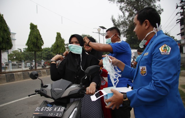 Pengurus KNPI Aceh Utara membagikan masker kepada pengguna jalan di persimpangan lampu merah Kota Lhoksukon, Kamis sore (23/9/2019). Foto: Fadel Aziz Pase