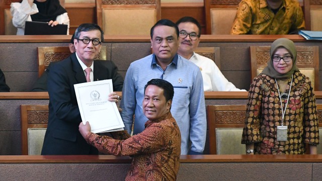 Menkumham Yasonna Laoly (kiri) menerima hasil revisi Undang-Undang (UU) Nomor 30 Tahun 2002 tentang Komisi Pemberantasan Korupsi (KPK) dari Ketua Badan Legislasi (Baleg) DPR Supratman Andi Agtas (kedua kiri). Foto: ANTARA FOTO/M Risyal Hidayat