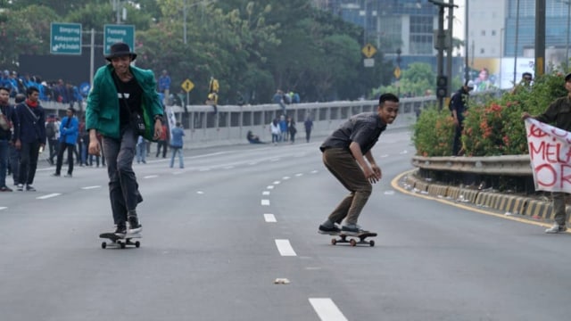 Dua orang mahasiswa bermain skateboard saat demo di depan gedung DPR RI, pada Selasa (24/9/2019). Foto: Helmi Afandi/kumparan