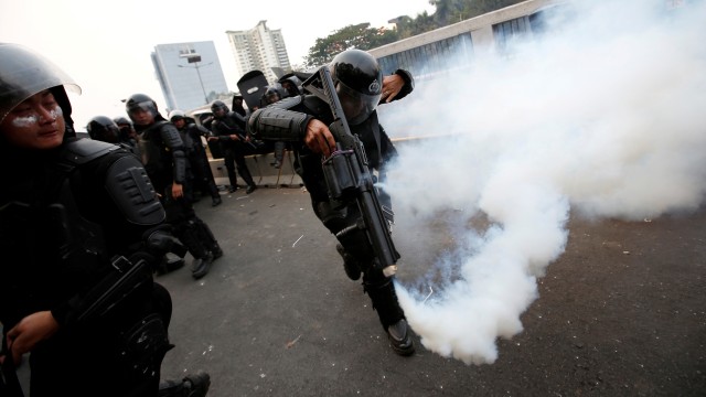 Salah satu anggota polisi menembakkan gas air mata di depan Gedung DPR, Selasa (24/9/2019). Foto: REUTERS/Willy Kurniawan