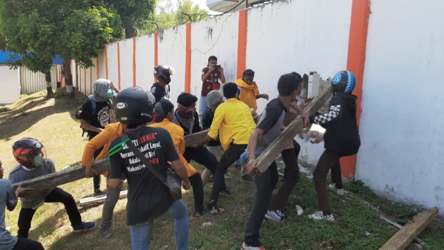 Beberapa demonstran sedang mencoba menjebol pagar beton gedung DPRD Sultra. Foto: Lukman Budianto/kendarinesia.