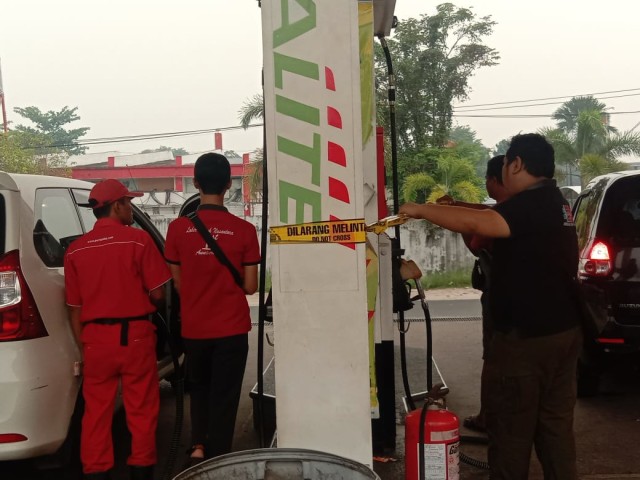 Polsek Pahandut memasang garis polisi pada mesin SPBU di Imam Bonjol Kota Palangka Raya. (Foto: Arnoldus)