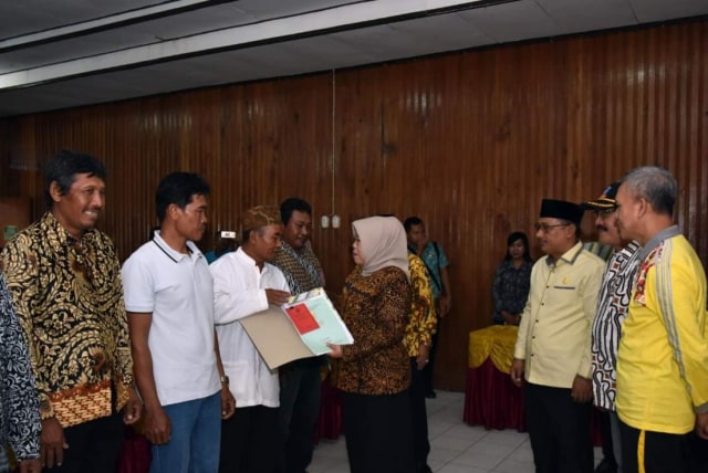 Bupati Kobar Nurhidayah menyerahkan sertifikat program PTSL 2018 kepada warga. (Foto: Prokom Kobar)
