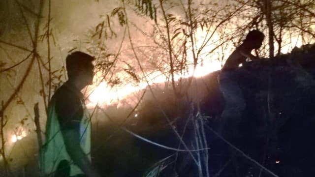 Personel Polsek Pamboang bersama warga berusaha memadamkan kebakaran lahan di Lingkungan Taduang, Kecamatan Lalampanua, Kecamatan Pamboang, Majene. Foto: Dok. Polsek Pamboang