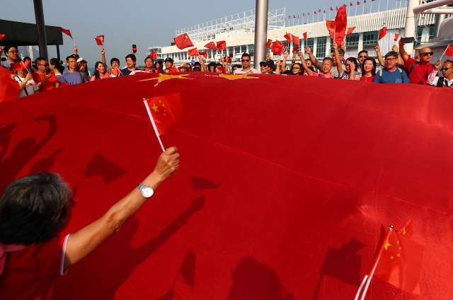 Pendukung pro China mengibaran bendera besar China saat perayaan Hari Nasional Republik Rakyat Tiongkok. Foto: REUTERS/Tyrone Siu