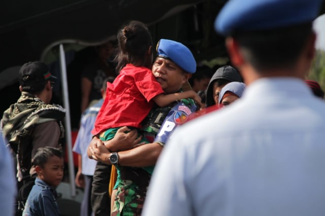 Salah seorang tentara menggendong anak yang baru tiba di Lanud Abdulrachman Saleh, Malang, Rabu (2/10). Foto: bayu eka novanta/tugumalang.id