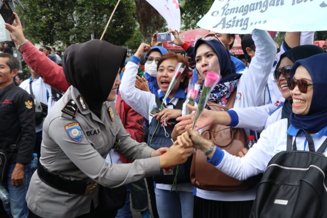 Polisi wanita membagi-bagikan air mineral dan bunga kepada buruh di Bandung. Foto: Dok. Humas Polrestabes Bandung