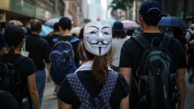 Seorang demonstran menutup wajahnya dengan topeng V For Vendetta saat protes di Hong Kong. Foto: AFP/Yan ZHAO