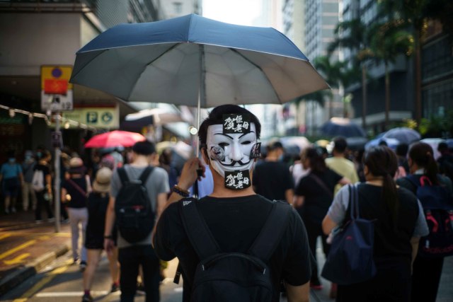 Seorang demonstran menutup wajahnya dengan topeng V For Vendetta saat protes di Hong Kong. Foto: AFP/Yan ZHAO