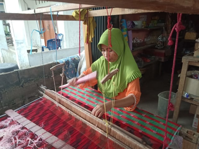 Seorang pengrajin sedang menenun di Kampung Wisata Tenun Khatulistiwa, Pontianak, Kalbar. Foto: Resi Jesita/Hi!Pontianak