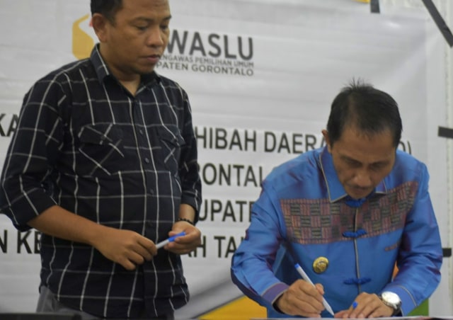 Bupati Gorontalo, Nelson Pomalingo, menandatangani  naskah perjanjian hibah daerah (NPHD) Kabupaten Gorontalo, dengan Komisi Pemilihan Umum (KPU) dan badan pengawas pemilihan umum (Bawaslu), Jumat, (04/10). Foto : Humas Pemkab 