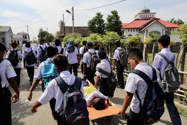 Siswa mengevakuasi rekannya yang luka-luka saat mengikuti simulasi gempa dan tsunami. Foto: Suparta/acehkini