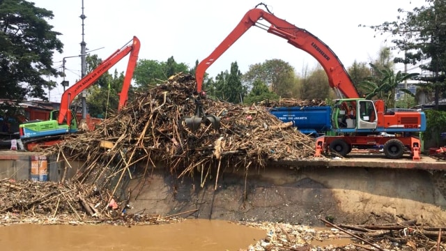 Petugas dibantu alat berat mengangkut sampah dari Pintu Air Manggarai, Jakarta, Rabu (9/10/2019). Foto: Andesta Herli Wijaya/kumparan