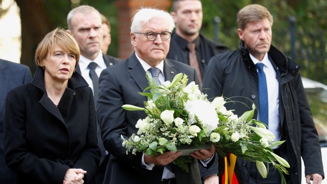 Presiden Jerman Frank-Walter Steinmeier (tengah) memegang bunga di luar sinagoga di Halle, Jerman. Foto: REUTERS / Hannibal Hanschke