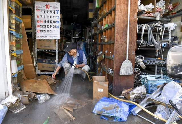 Penjaga toko membersihkan bekas banjir di area toko. Foto: AFP/William West