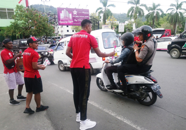 Tim Sepakbola Persipura Jayapura turun ke jalan membagikan bunga kepada warga Kota Jayapura sebagai sikap peduli kedamaian di Papua. (BumiPapua.com/Pratiwi)