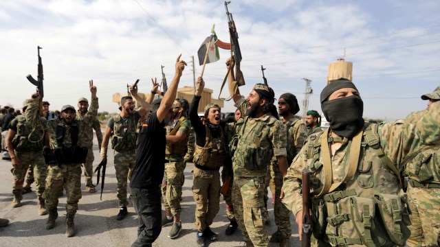 Pejuang pemberontak yang didukung Turki bereaksi ketika mereka memegang senjata di kota perbatasan Tel Abyad Foto: Reuters