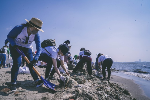 Peserta bersih-bersih pantai "Menghadap Laut 2019" di Pantai Timur Kelurahan Ancol, Jakarta Utara, Minggu (18/8/2019). Sampah tekstil yang telah menyatu dengan pasir pantai jamak ditemui dan sulit dibersihkan.