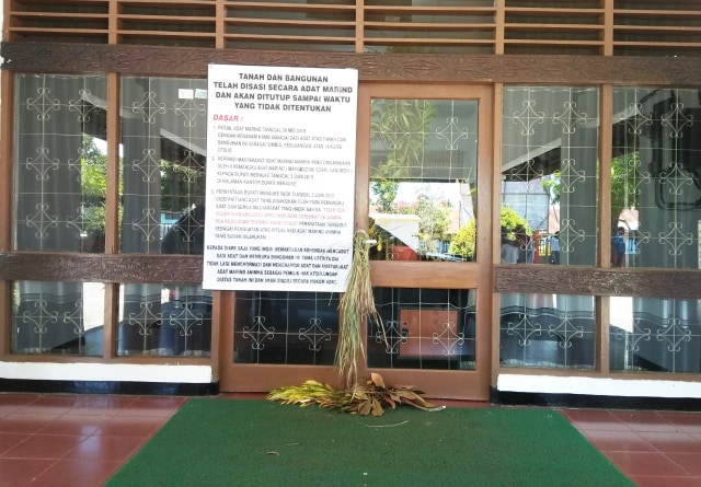 Pintu utama Kantor DPRD Merauke yang dipalang masyarakat adat Marind dengan pemasangan sasi dan pamflet berisi tuntutan. (Foto Abdel)