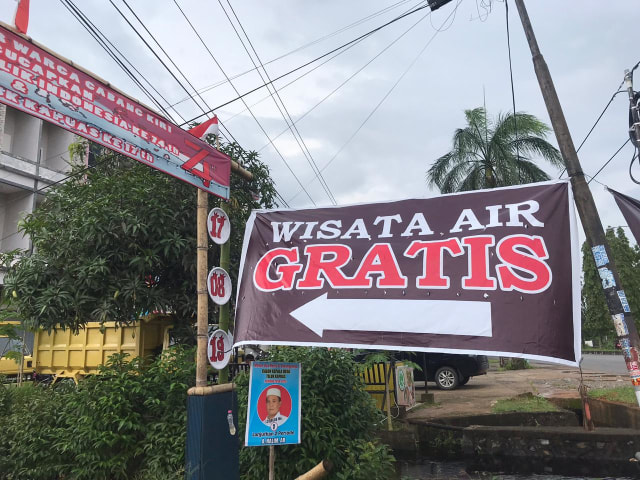 Warga Parit Cabang Kiri memasang banner Wisata Air Gratis di depan gapura. Foto: Teri/Hi!Pontianak
