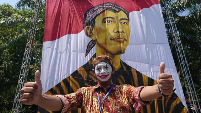 Salah satu warga berfoto bersama bendera raksasa di Plaza Manahan. (Agung Santoso)