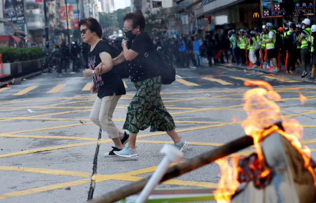 Seorang warga melewati kerusuhan saat demo di Hong Kong. Foto: Reuters