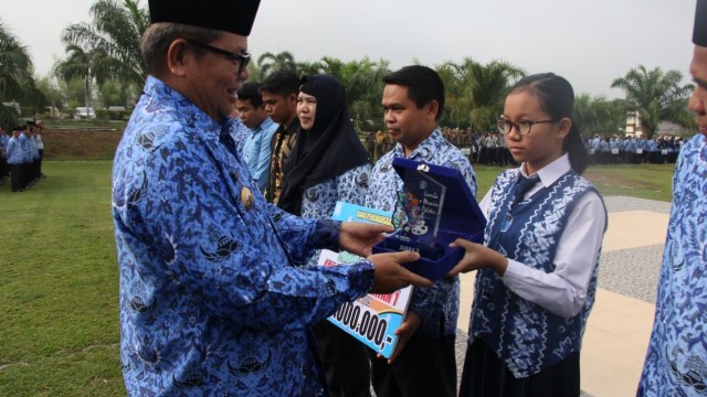 Bupati Balangan H Ansharuddin menyerahkan penghargaan ke siswi SMPN 1 Halong peraih juara FLS2N, Senin (21/10/2019). Foto: Diskominfo Balangan