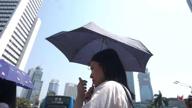 Seorang warga menggunakan payung guna terhindar dari panasnya matahari, Jakarta, pada Selasa (22/10/2019). Foto: Iqbal Firdaus/kumparan