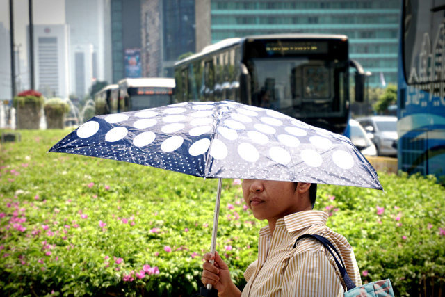 Seorang warga menggunakan payung guna terhindar dari panasnya matahari, Jakarta, pada Selasa (22/10/2019). Foto: Iqbal Firdaus/kumparan