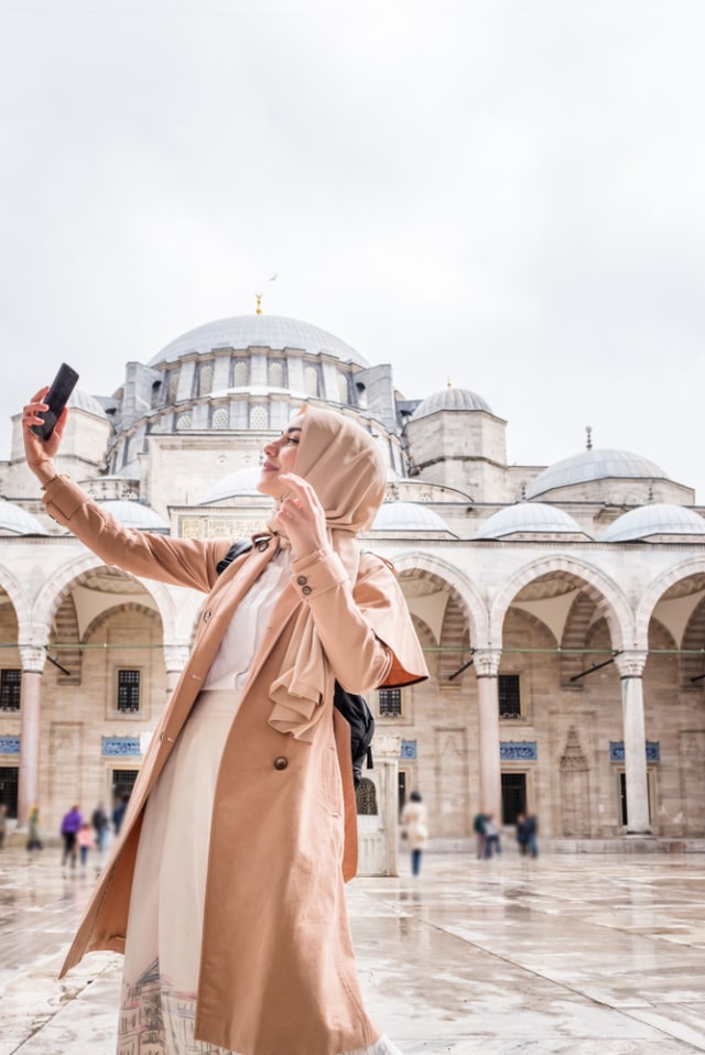 Ilustrasi solo traveler wanita Muslim sedang berselfie. Foto: Shutterstock