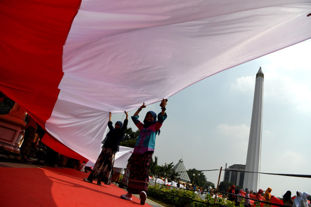 Sejumlah pelajar membentangkan bendera Merah Putih saat digelar Upacara Sumpah Merah Putih dalam rangka peringatan Hari Sumpah Pemuda di lapangan Tugu Pahlawan. Foto: ANTARA FOTO/Zabur Karuru