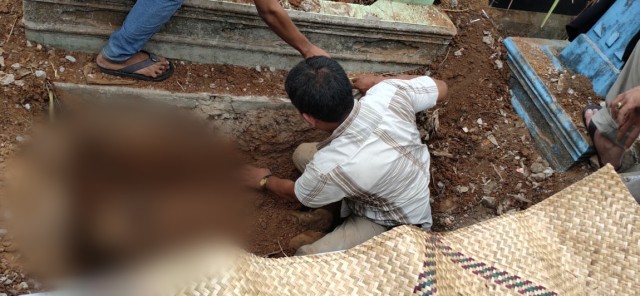 Petugas saat menggangkat jasad korban yang dicor dalam lubang air di TPU Kandang Kawat. (foto: istimewa)